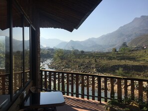 A balcony with a view of a river and mountains.