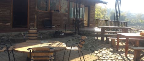 Un edificio de madera rústico con un patio que tiene mesas redondas y sillas de mimbre.