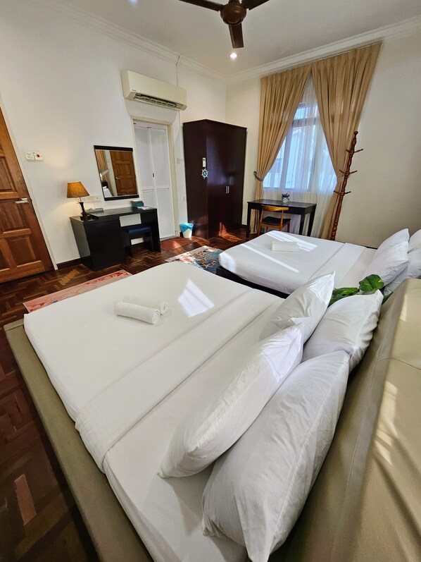 A hotel room with a bed, a desk, a chair, a wardrobe, and a ceiling fan. - Little Heaven by SkyHive BeachfrontVilla (George Town)