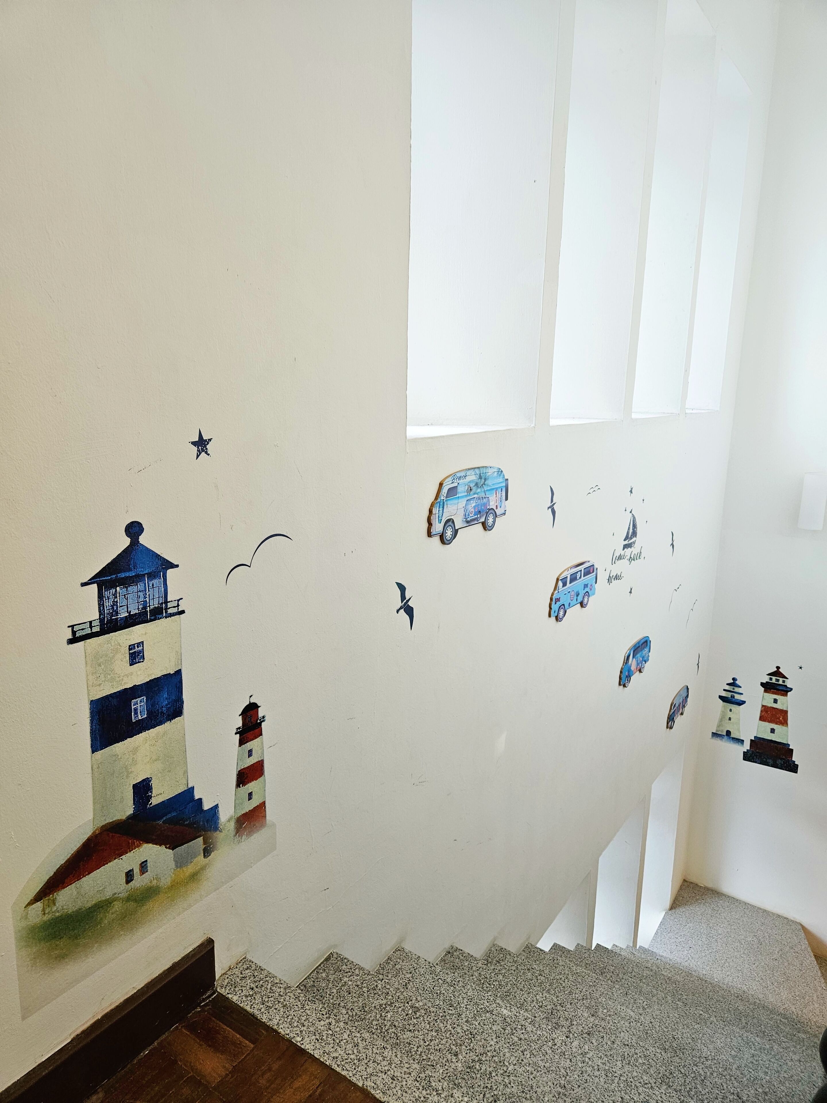 A staircase with a wall decorated with maritime-themed stickers, including lighthouses and vehicles.
