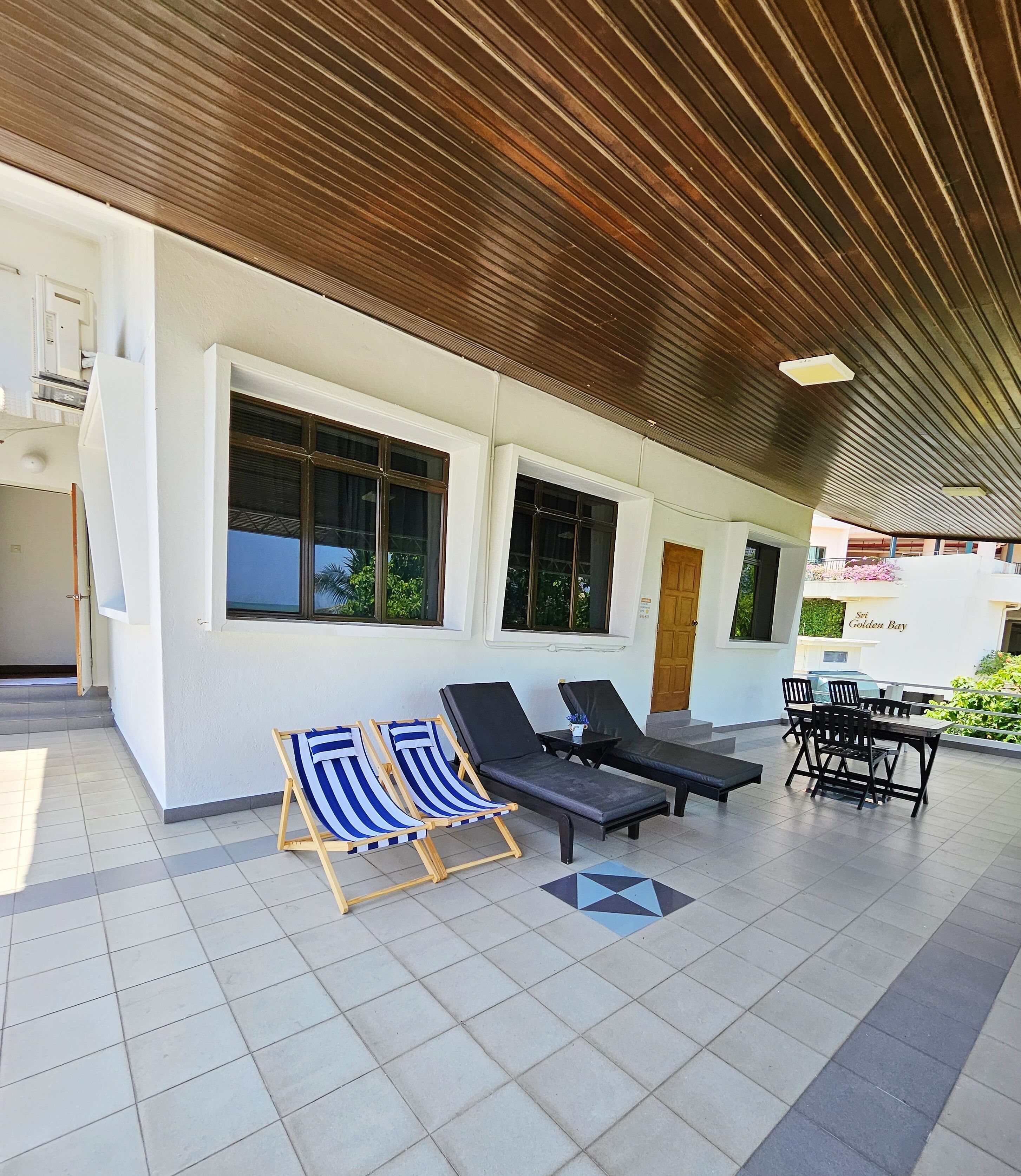 A covered outdoor area with two lounge chairs, a table, and a bench.