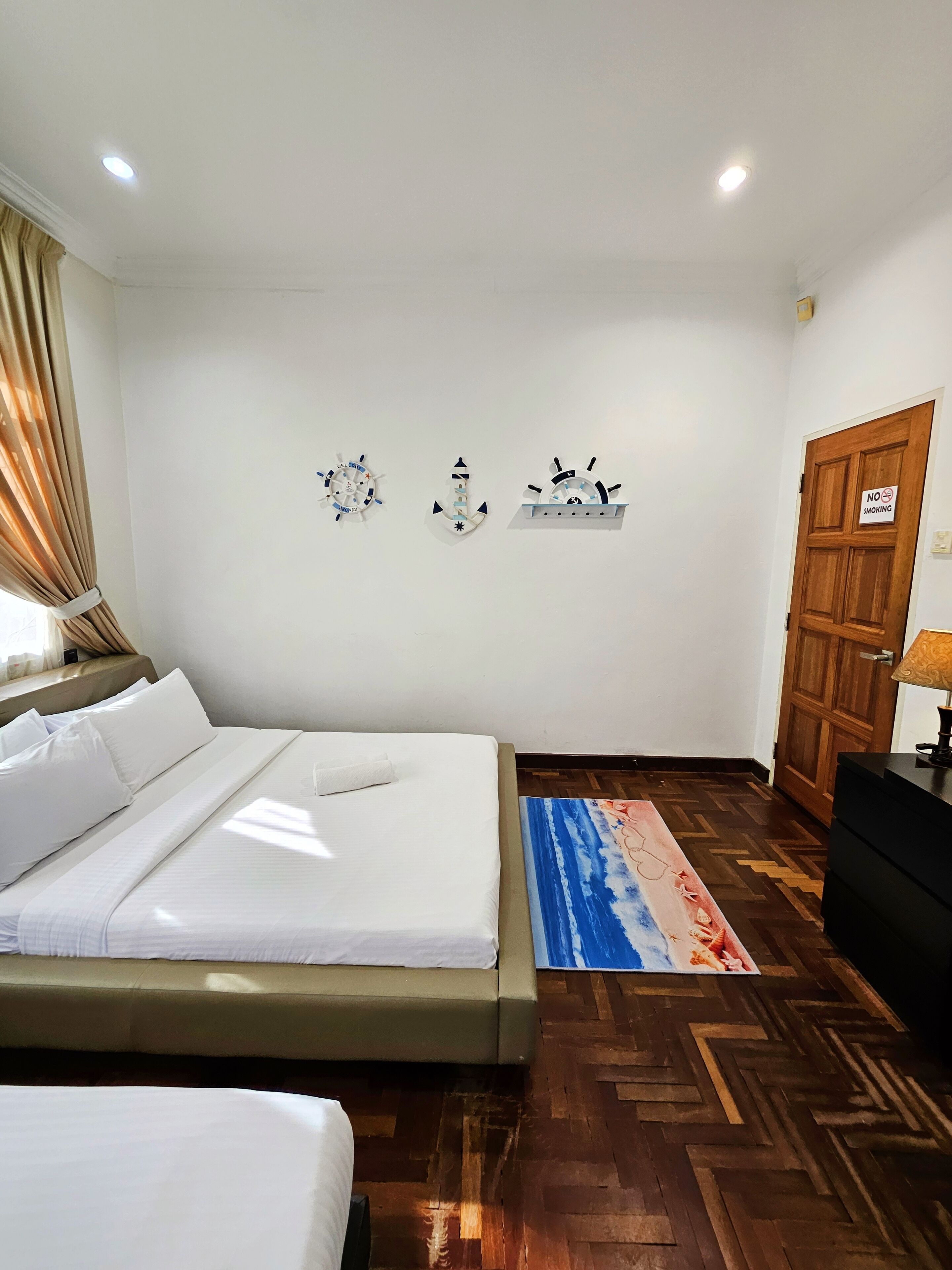 Una camera d'albergo con un letto, pavimento in legno, cartello 'No Smoking' e decorazioni a parete.