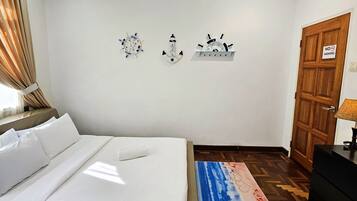 Una camera d'albergo con un letto, pavimento in legno, cartello 'No Smoking' e decorazioni a parete.