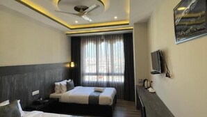 A hotel room with two beds, a desk, a ceiling fan, and a painting on the wall. - Yang Bhutan Hotel (Paro)