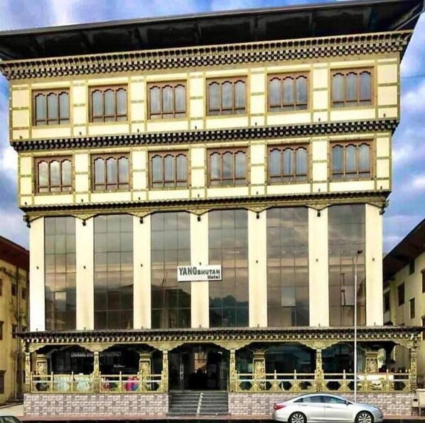 A multi-story building with large windows and a sign reading "YANG BHUTAN Hotel".