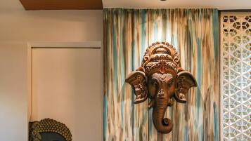 A room with a patterned floor, a blue armchair, a decorative elephant head, and a Buddha head sculpture.