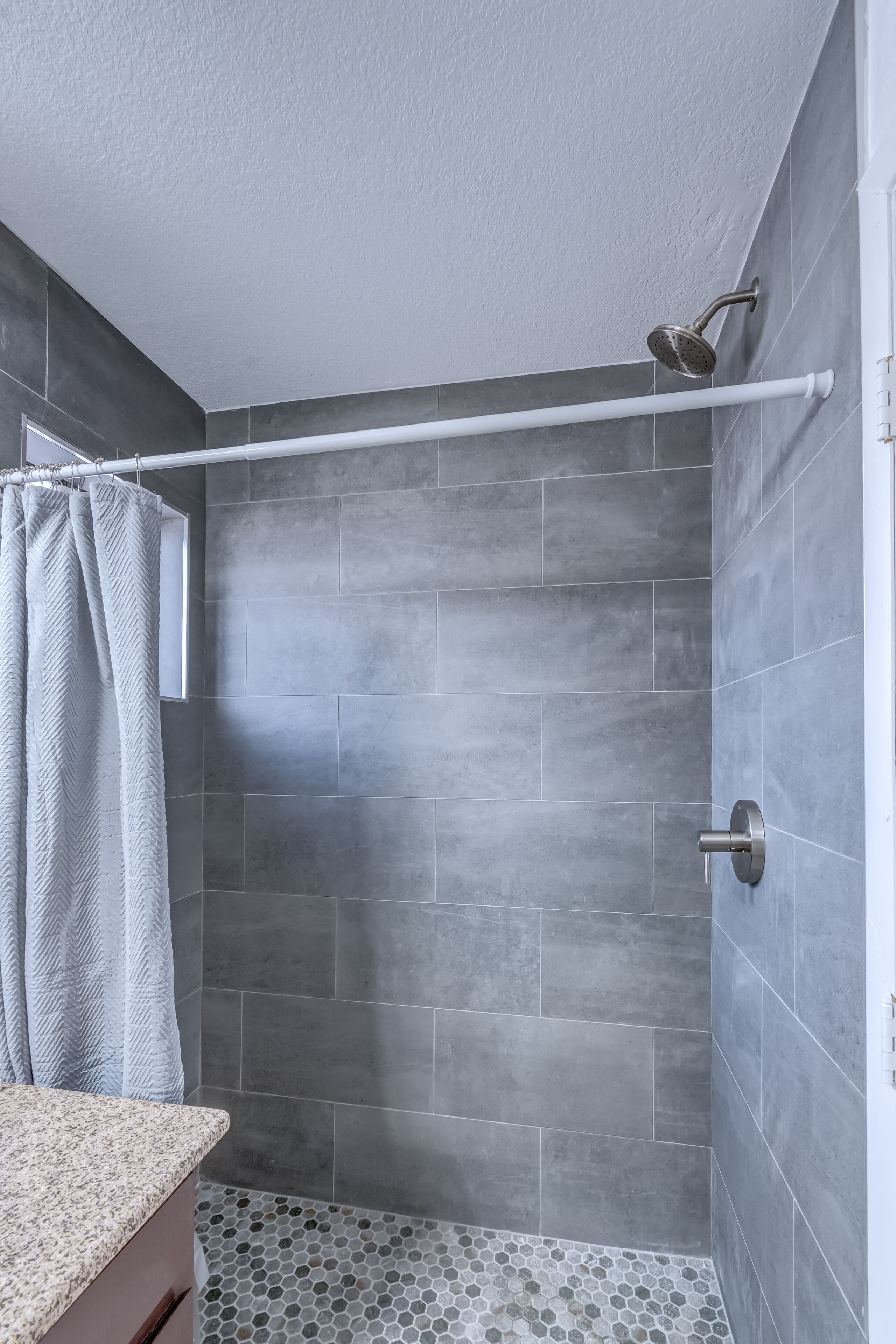 A shower with a rain showerhead, a towel rack, and a shower curtain.