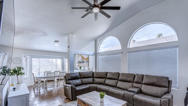 A spacious living room with a sectional sofa, a coffee table, and a dining area with a table and chairs.