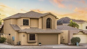 A single-story house with a garage, a small front yard, and a mountain in the background.