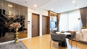 A modern hotel room with a dining area, a sofa set, and a large mirror. - The LUMIERE Riverside Residence (Ho Chi Minh City)