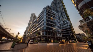 A modern high-rise building with a curved facade, multiple balconies, and a well-lit entrance area. - The LUMIERE Riverside Residence (Ho Chi Minh City)