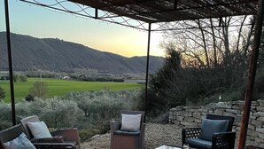 An outdoor patio with wicker furniture, a stone wall, and a fire pit.