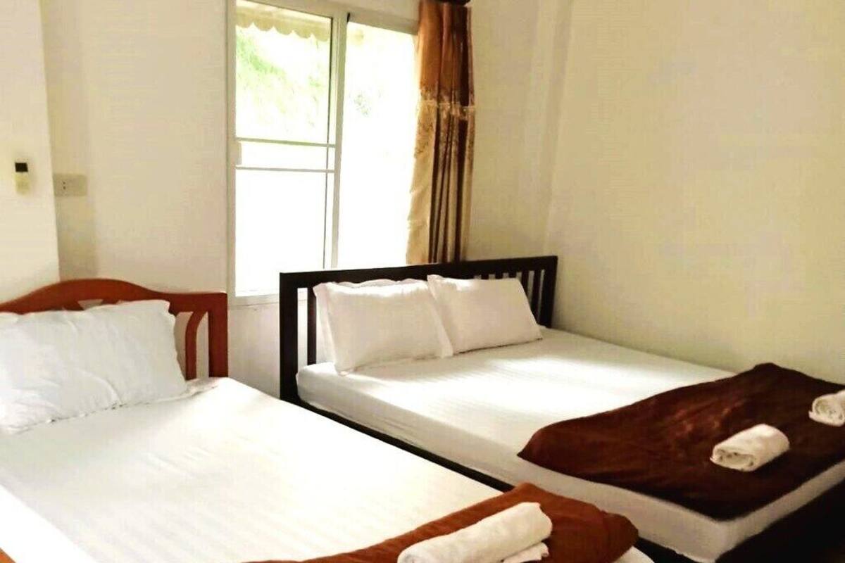 A hotel room with two single beds, each with a brown blanket and white pillow.