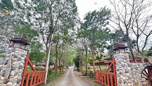 A gravel path leading through a gated entrance with stone walls and red gates.