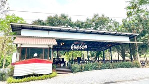 A restaurant with a covered outdoor seating area, a small boat-like structure, and a signboard.