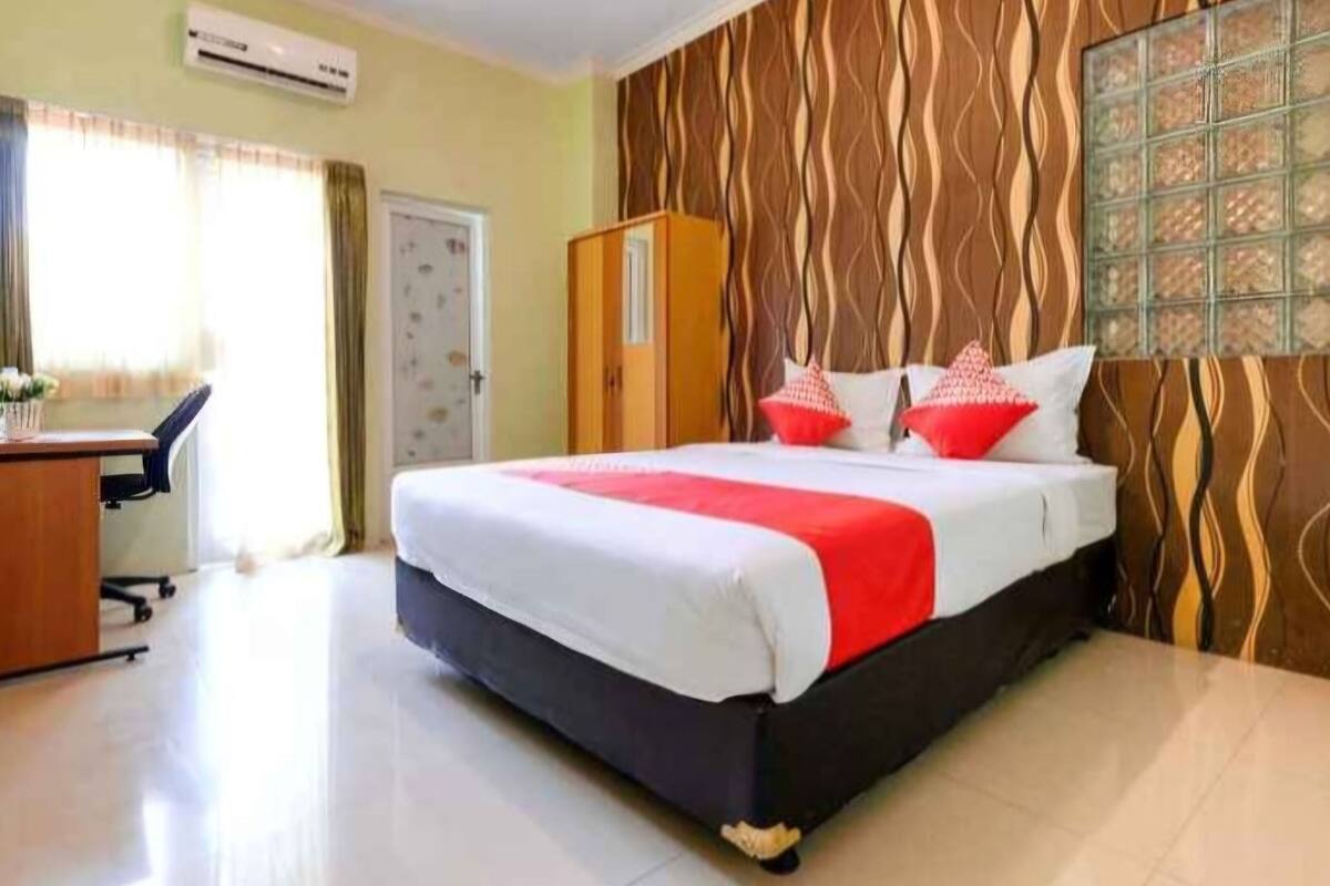 A hotel room with a bed, a desk, and a wardrobe.