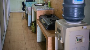 A compact kitchen with a gas stove, a water dispenser, and a sink. - Omah Manahan (Surakarta)
