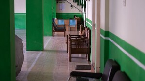 A hallway with green walls, wooden benches, and a staircase in the background. - Omah Manahan (Surakarta)