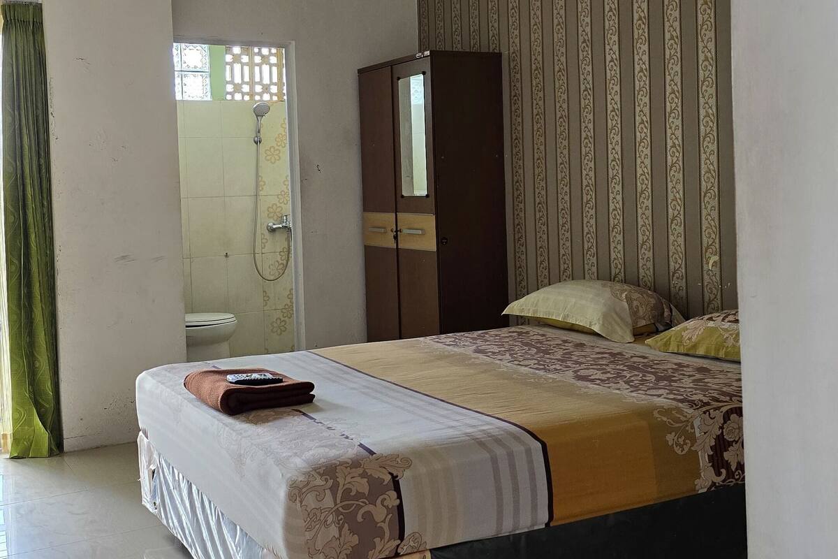 A bedroom with a bed, a wardrobe, a shower, and a toilet.