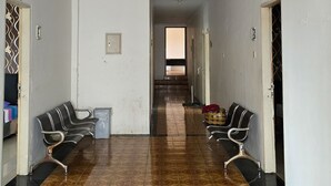 A hallway with patterned floor tiles, two rows of black and white chairs, and doors on either side. - Omah Manahan (Surakarta)