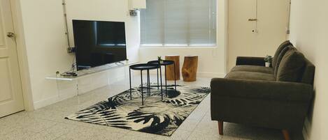 Una sala de estar con un televisor de pantalla plana, un sofá, una mesa de centro y una alfombra con estampado de cebra.