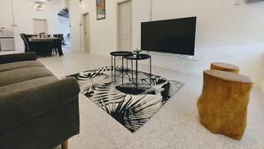 A modern living room with a sofa, a coffee table, a TV, and a patterned rug. - Garden Home Ipoh (Ipoh)