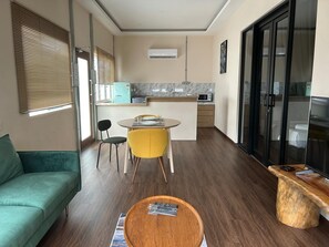 Un espace de vie compact comprenant un canapé, une table à manger avec des chaises, un coin cuisine avec un four à micro-ondes et un téléviseur.
