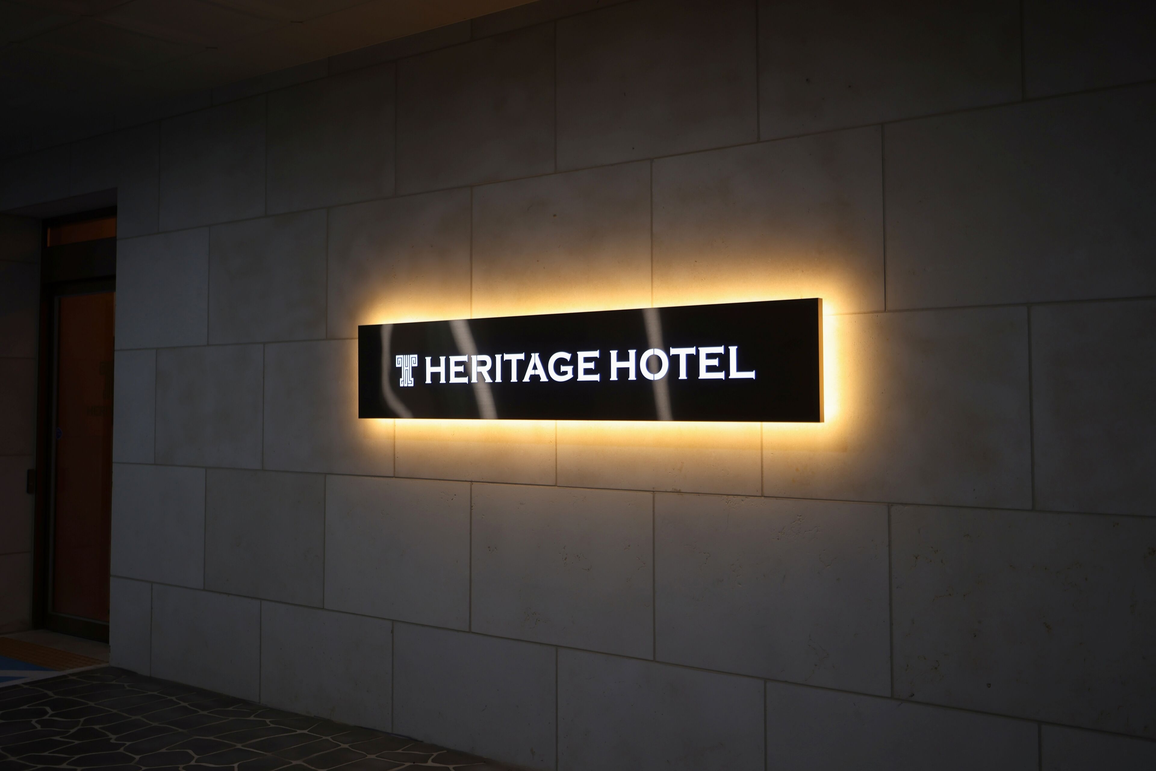 A sign for the Heritage Hotel with a modern design and illuminated lettering.