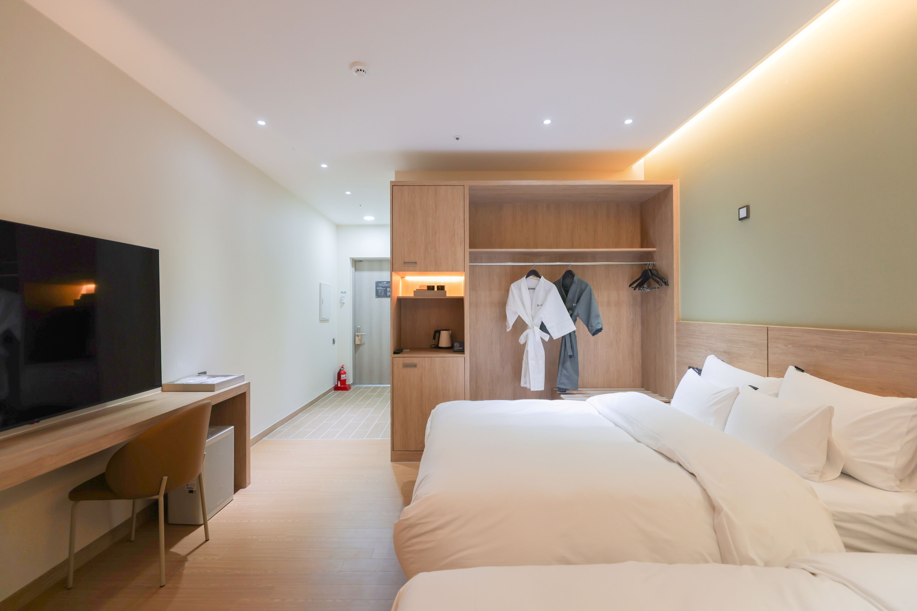 A hotel room with a bed, a TV, a desk, and a wardrobe.