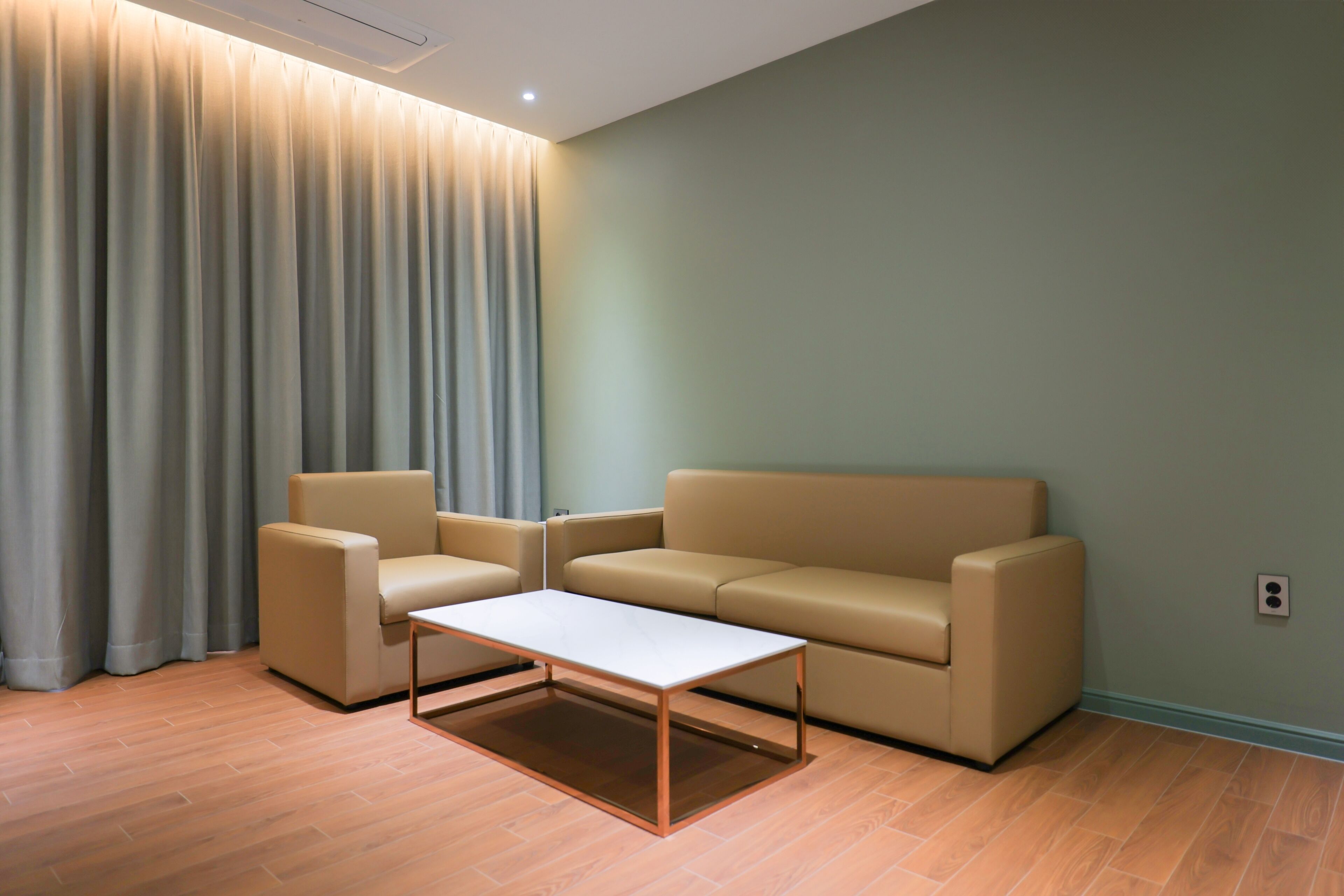 Een moderne woonkamer met een beige bank, een bijpassende fauteuil en een salontafel.