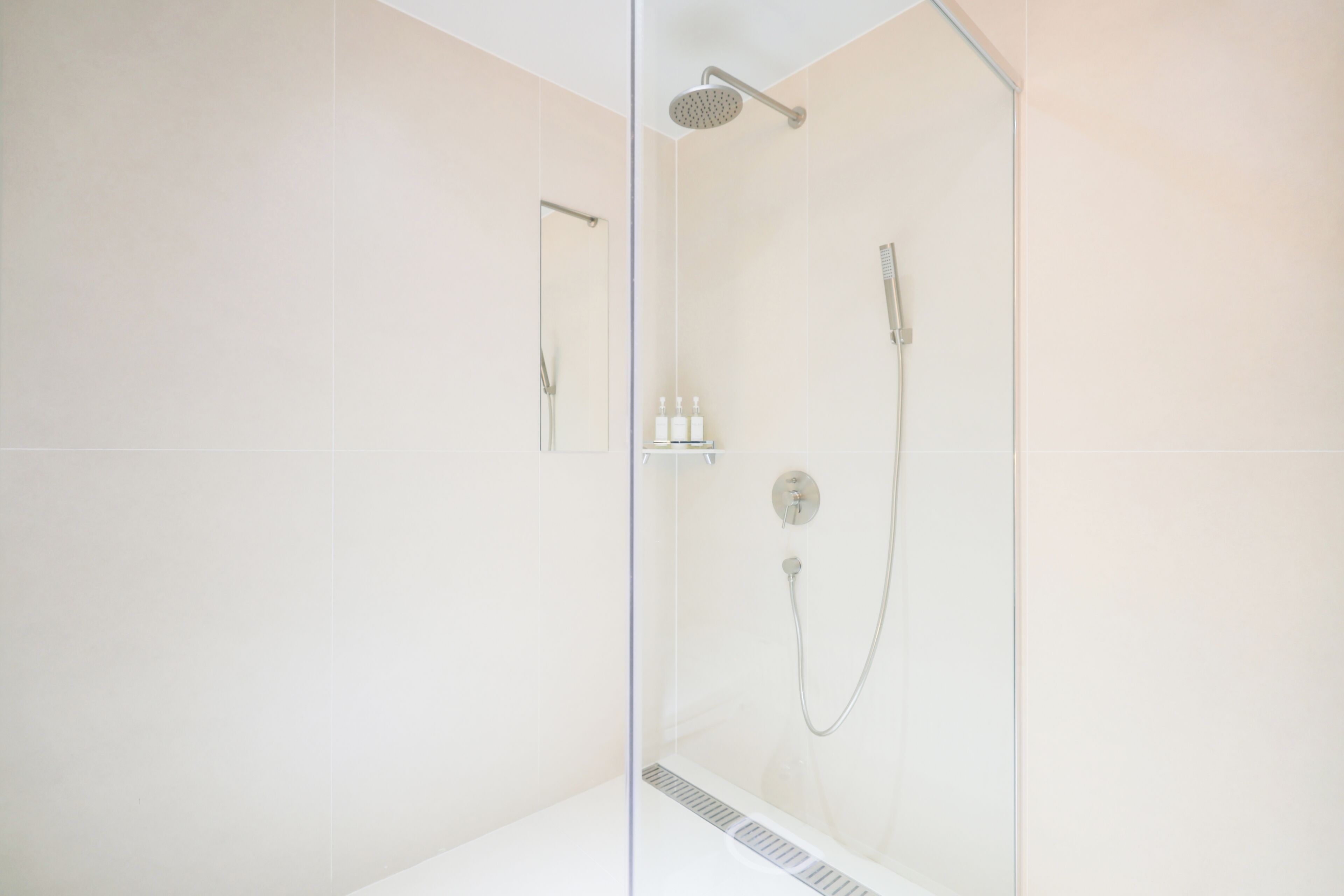 Un bagno moderno con doccia vetrata, soffione a mano e rubinetto a parete.