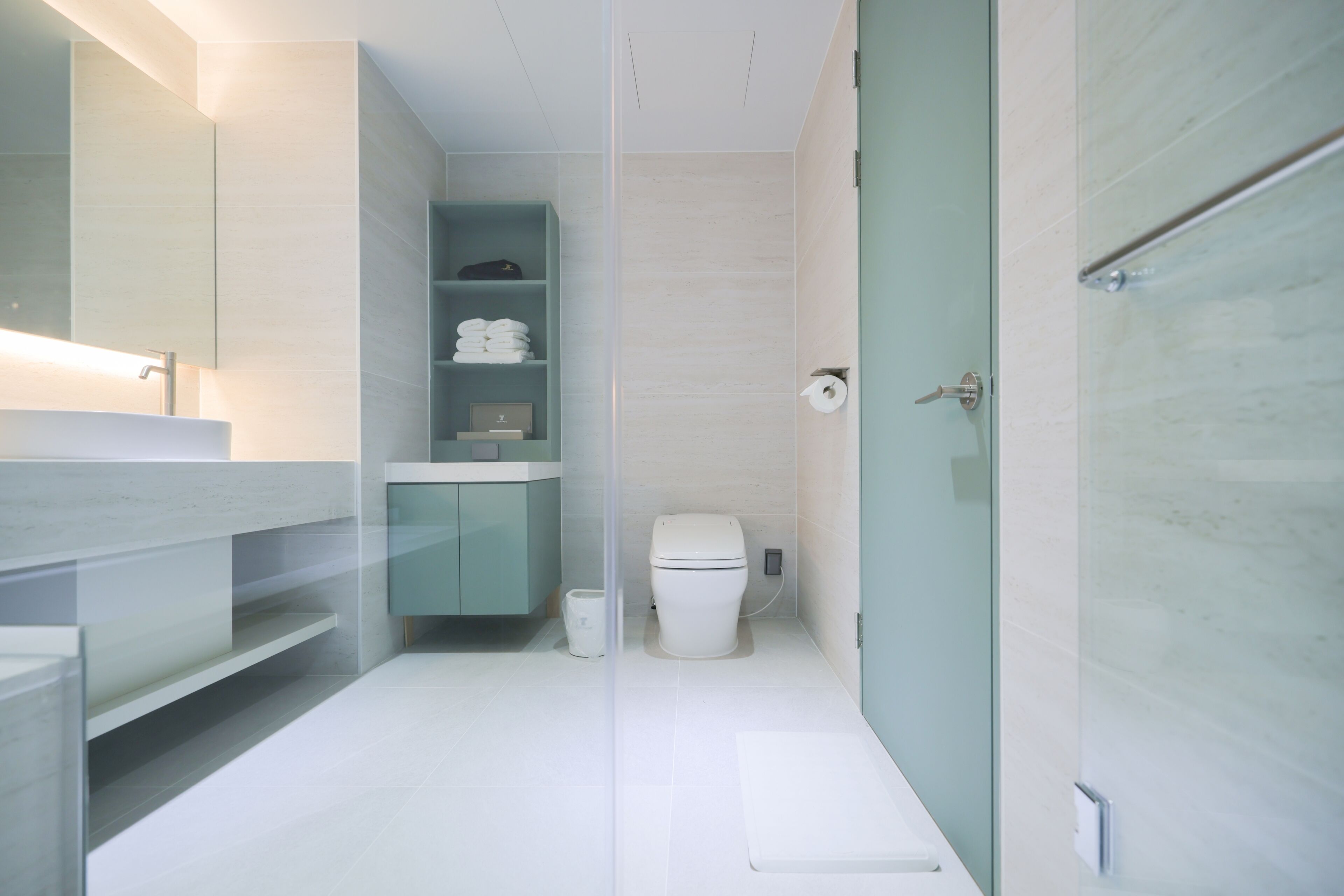 Un baño moderno con cabina de ducha de vidrio, inodoro y lavamanos con espejo.