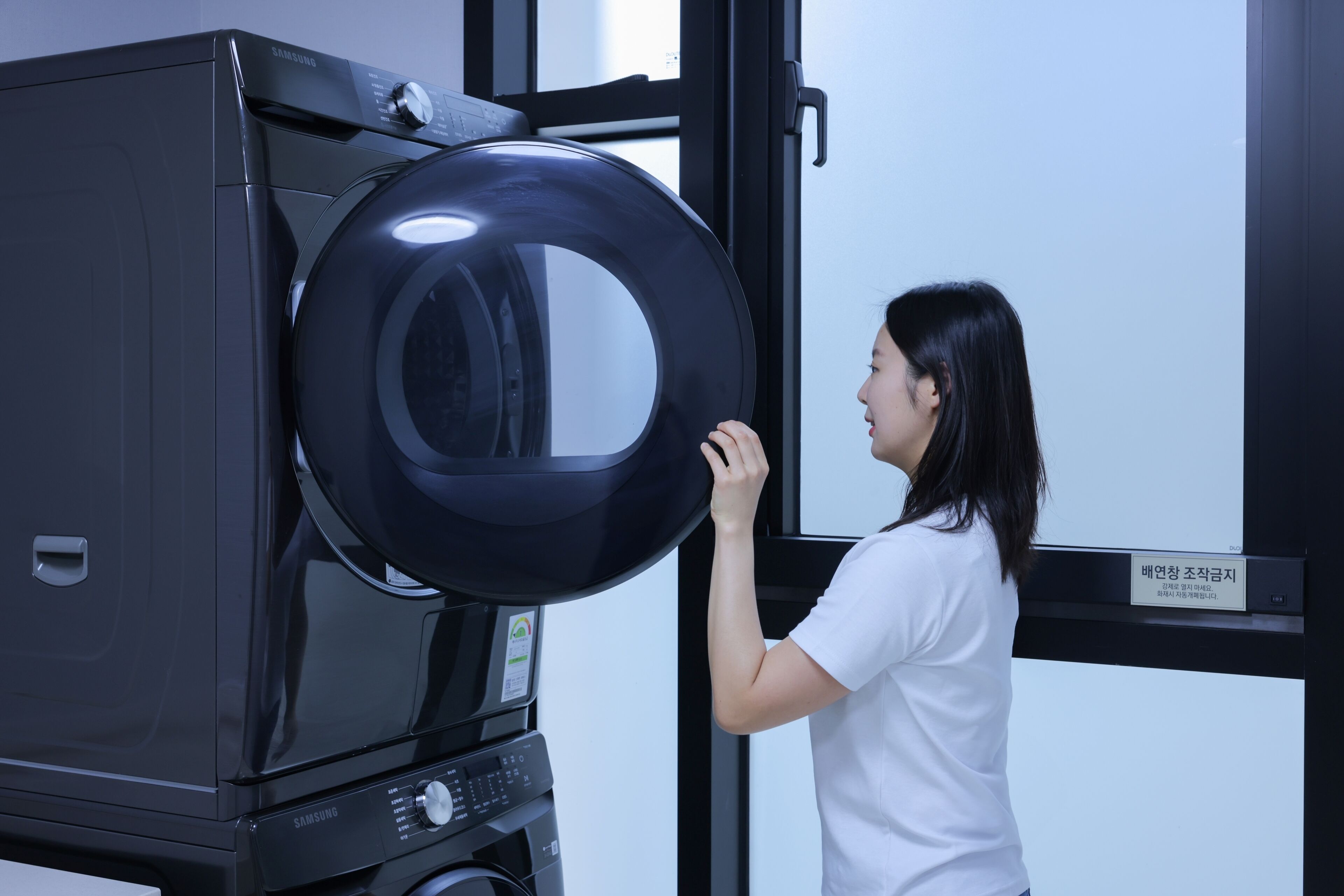 Una persona interactuando con un electrodoméstico grande, negro y circular, posiblemente un microondas o un horno, en una cocina moderna.