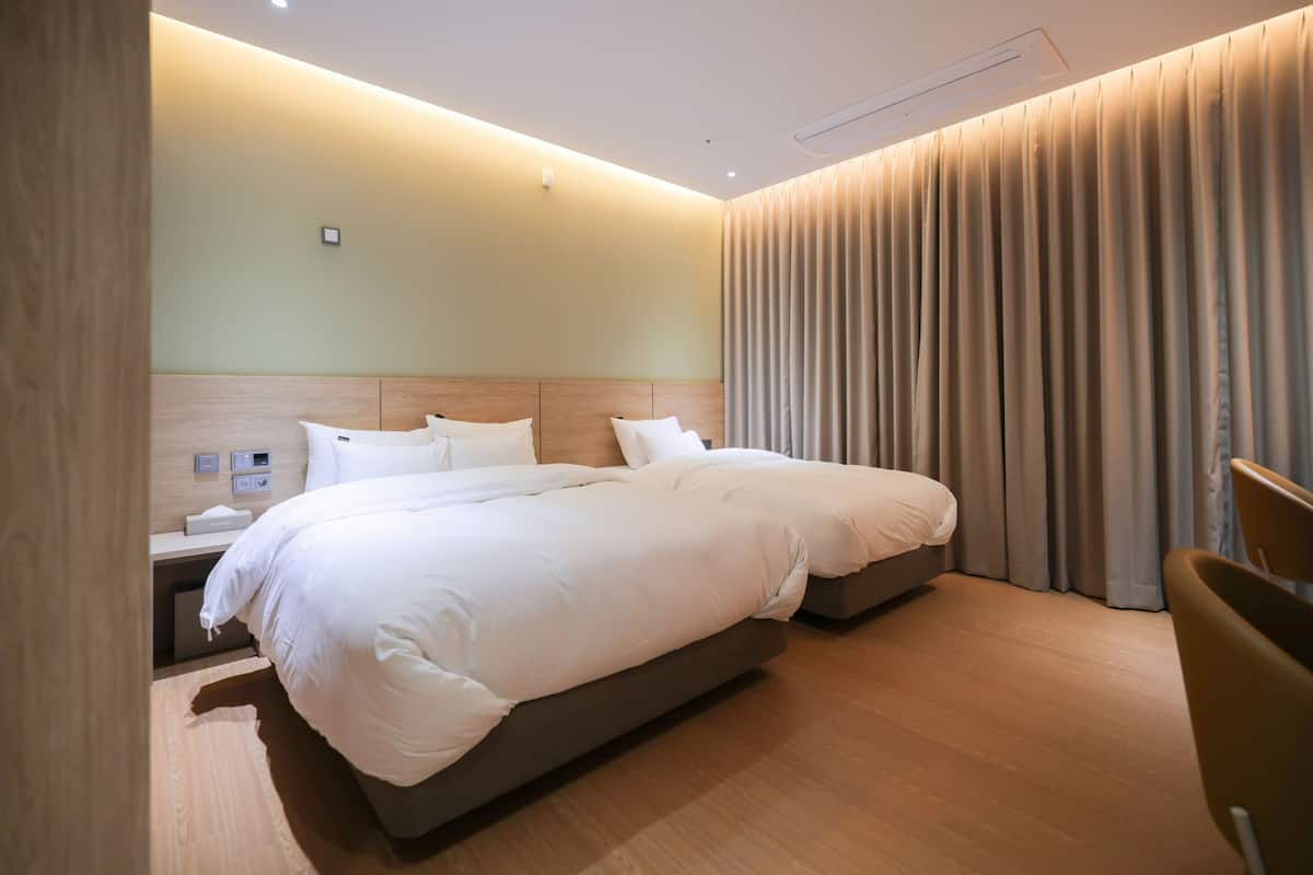 A modern hotel room with a large bed, bedside tables, and a curtain.