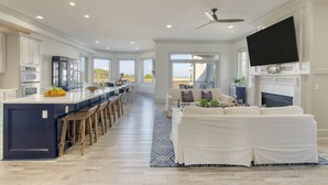 Une cuisine spacieuse dotée d’un grand îlot central, d’un coin repas et d’un salon agrémenté d’une cheminée.