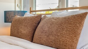 A bed with brown textured pillows and a white comforter. - Conway | Professionally Managed Buyout in DT Nash (Nashville)