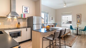 A modern kitchen with a central island, built-in microwave, and stainless steel appliances. - Conway | Professionally Managed Buyout in DT Nash (Nashville)