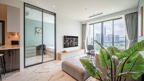 Un salon moderne avec une grande fenêtre, un canapé, un téléviseur et une plante.