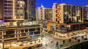 Un quartier urbain moderne, avec de hauts immeubles, un carrefour bien éclairé et une promenade piétonne.