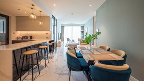 Une cuisine moderne dotée d’un coin bar, d’une table à manger avec des chaises et d’une grande fenêtre laissant entrer la lumière naturelle.