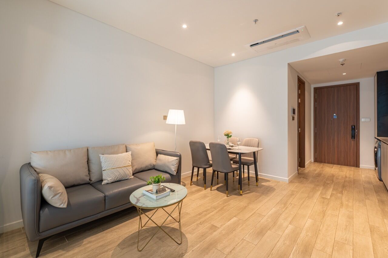 Ein modernes Wohnzimmer mit einer Couch, einem kleinen runden Tisch und einem Essbereich mit Stühlen.