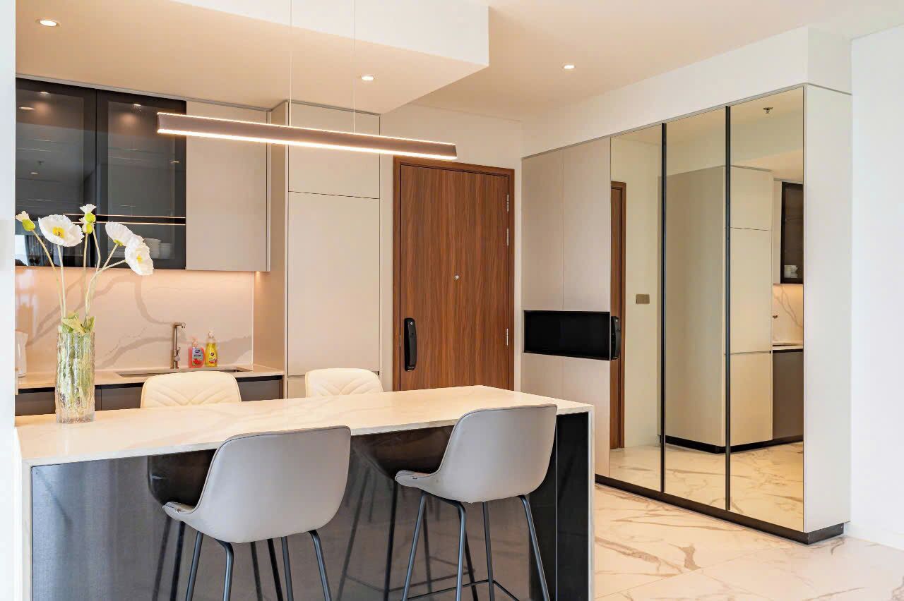 Une cuisine moderne avec un îlot central, des tabourets de bar blancs et une porte en bois.