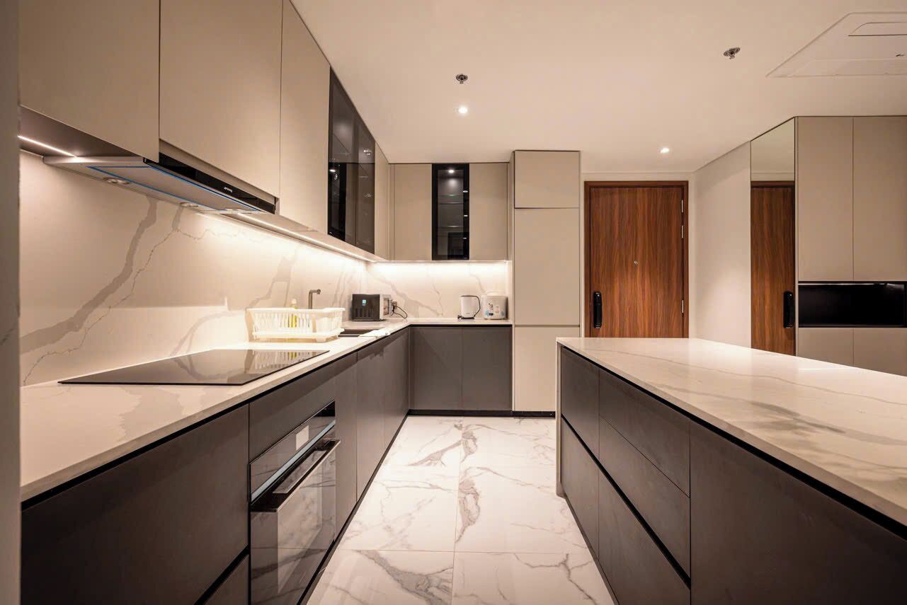 A modern kitchen with sleek cabinetry, a marble countertop, and built-in appliances.
