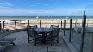 A terrace with a round table and chairs, overlooking a beach with sailboats. - Apartment in Nieuwpoort with Sea Views (Nieuwpoort)