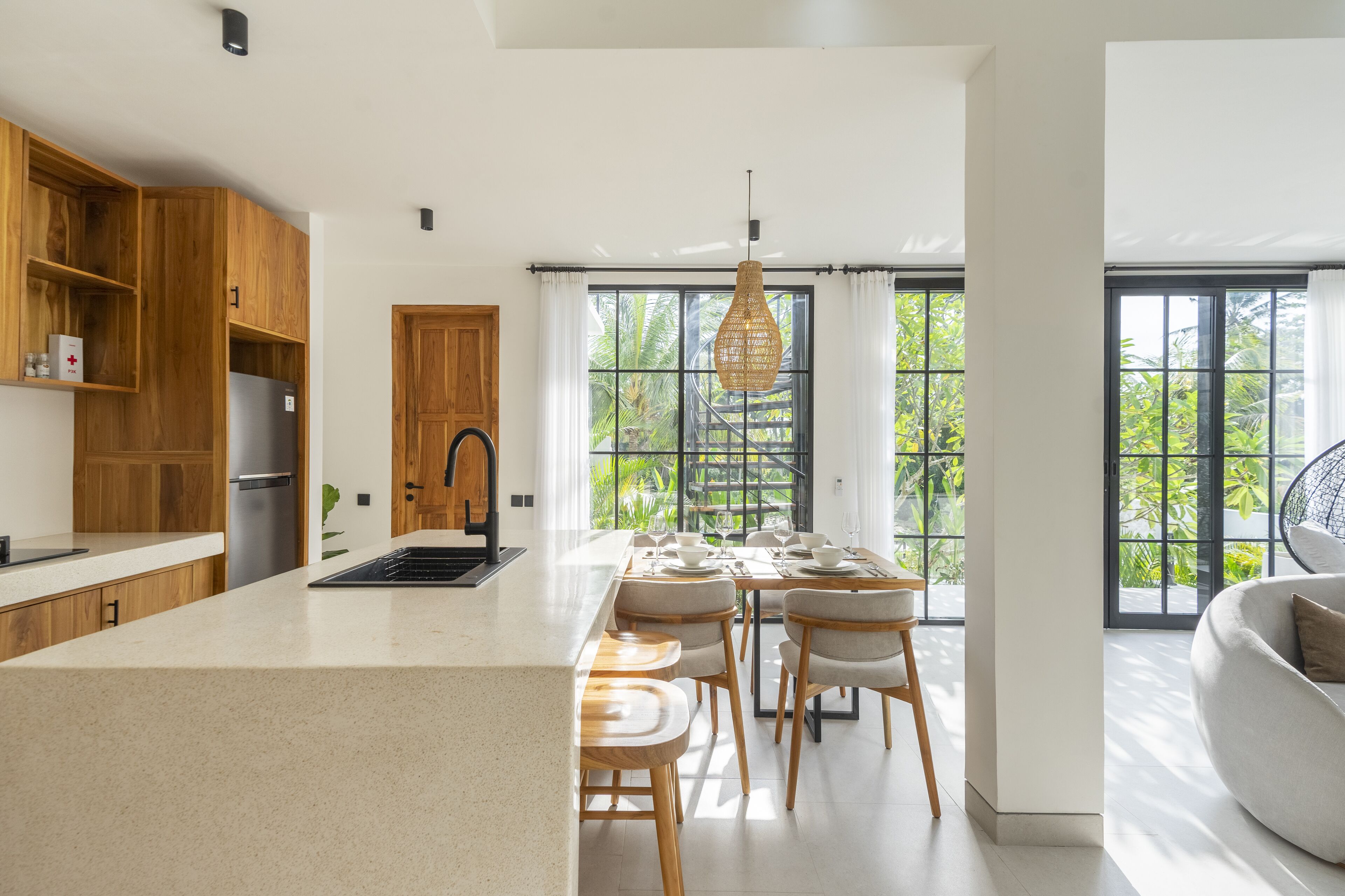 Una cocina moderna con armarios de madera, una isla central y un comedor con sillas y una mesa.