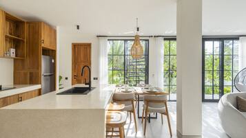 Una cocina moderna con armarios de madera, una isla central y un comedor con sillas y una mesa.