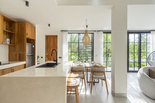 Una cocina moderna con armarios de madera, una isla central y un comedor con sillas y una mesa.