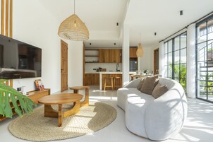 Una sala de estar moderna con un sofá, una mesa de centro de madera y un televisor.