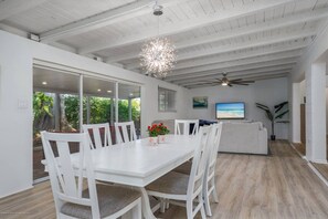 A spacious dining area with a white table and chairs, a ceiling fan, and a view of the outdoors. - Quiet Family Home | Modern | Dog Friendly (Sarasota)