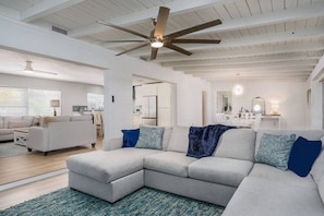 A spacious living area with a sectional sofa, a ceiling fan, and a view into the kitchen. - Quiet Family Home | Modern | Dog Friendly (Sarasota)